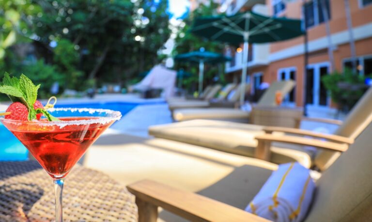 Drink in focus with lounge chairs and pool in the background at The Mutiny Hotel